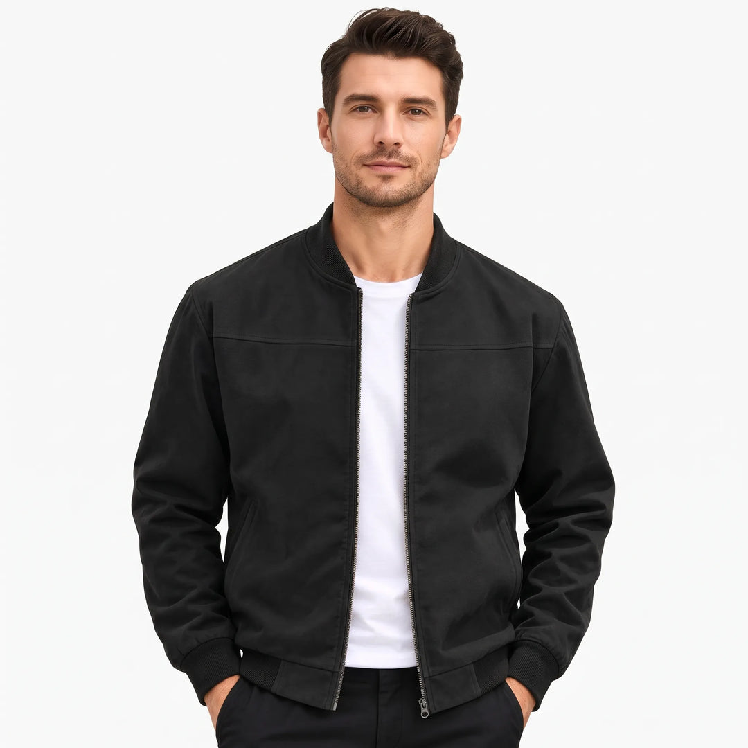 Studio shot of a man in the black bomber jacket, hands in dark pants pockets 49