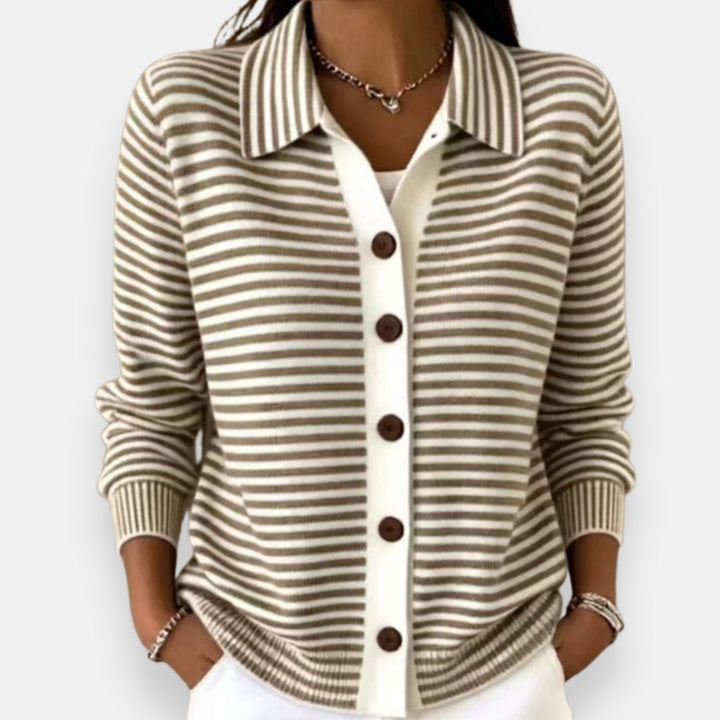 Woman wearing the collared cardigan in taupe and white stripes with brown buttons, white placket, ribbed cuffs, hands in pockets. 1