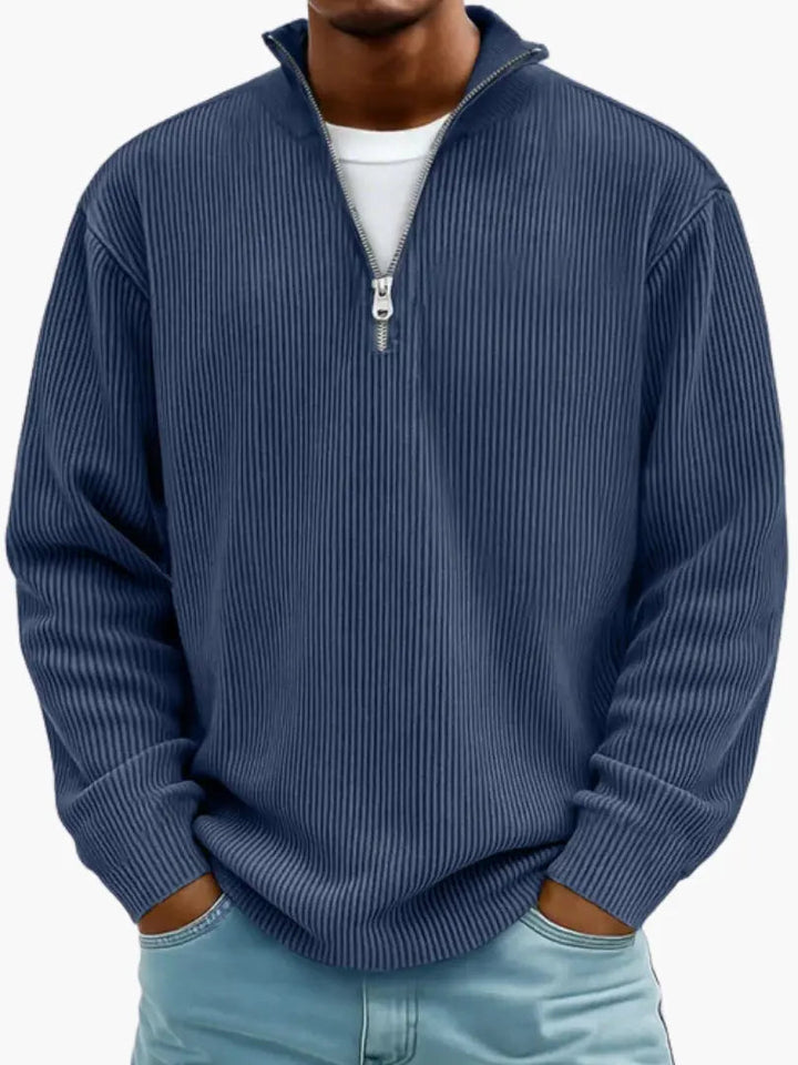Man wearing the ribbed quarter-zip sweater in navy blue over a white tee, hands in jeans pockets.