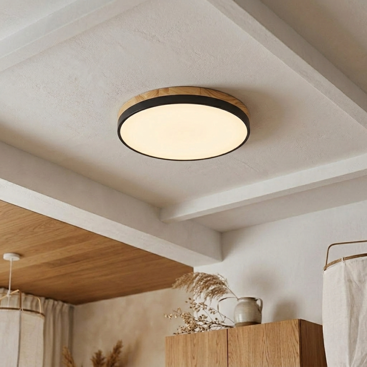 Black-banded disc ceiling light with a thick wood-grain upper ring glowing warm white on a beamed ceiling. 12