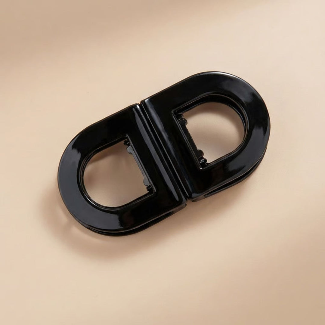 Flat Grip Magnetic Hair Clip in solid black, shown from above on a beige surface.