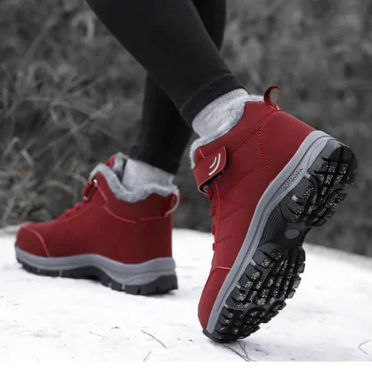 Person walking on snow in red fleece-lined boots, one sole lifted to show the tread 6