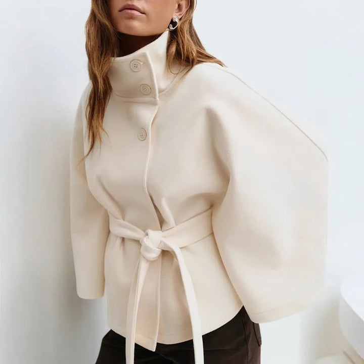 Cream cape jacket worn by a model in three-quarter view, belt knotted at the waist 4