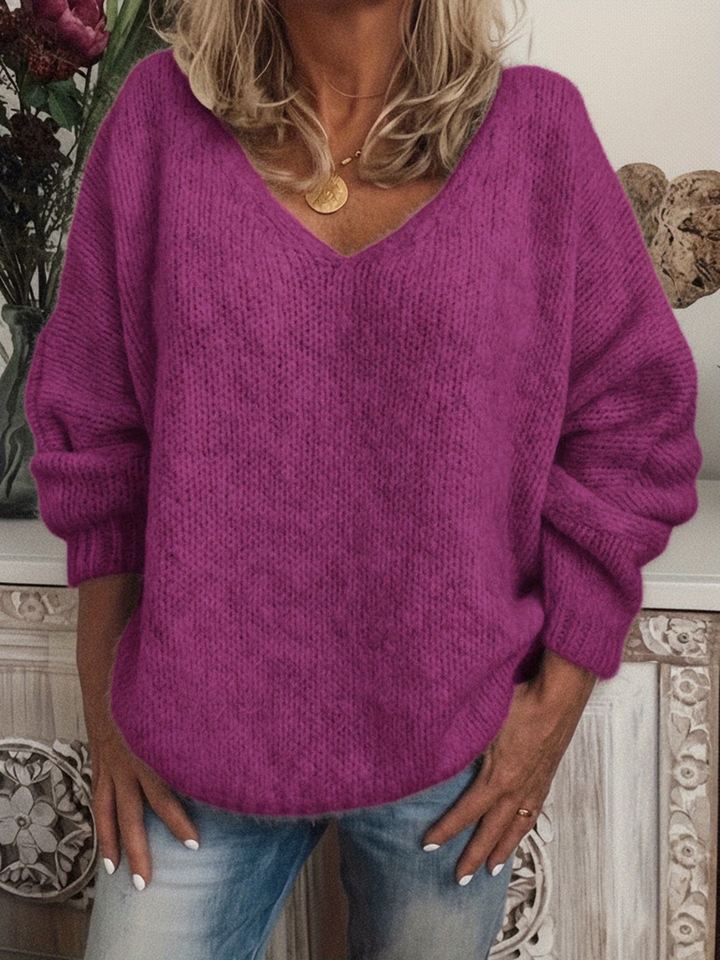 Magenta purple chunky knit sweater with V-neckline and relaxed sleeves, styled with jeans and a gold coin necklace.
