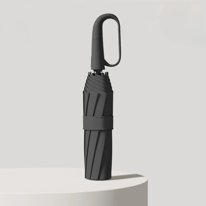 Closed folding umbrella in Black with an oval hook handle and fabric strap.