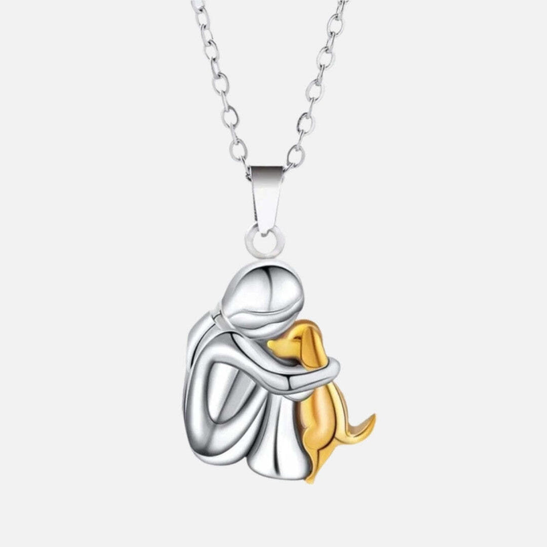 Close view of the two-tone pendant with a silver figure embracing a golden dog, on a silver chain.