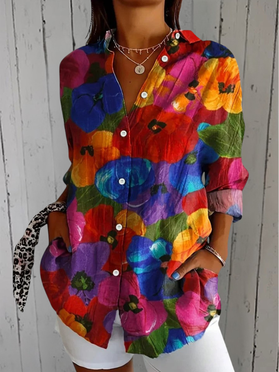 Anica blouse detail with a vivid print of large blue, red, orange and purple poppy-like flowers with green leaves.