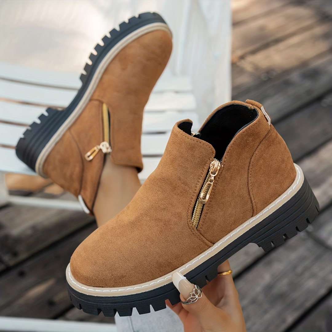 Tan brown suede-look ankle boots with gold side zippers and chunky lug soles.