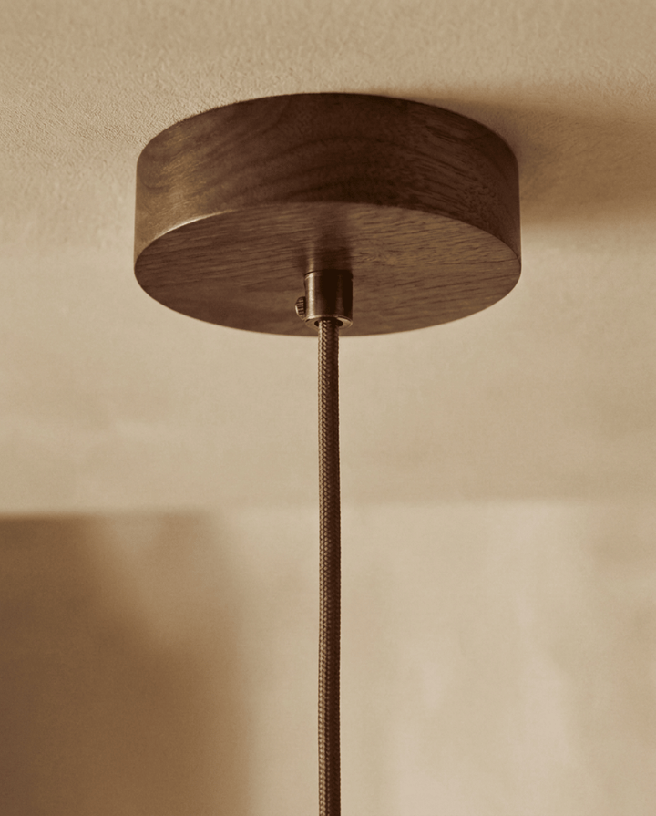 Travertine pendant light detail of the round dark wood ceiling canopy and braided brown cord.