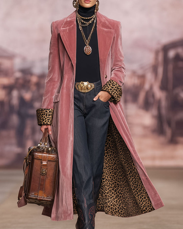 Model on a runway-style backdrop wearing the pink coat open, hand in pocket, with leopard-print cuffs and lining visible and a leather bag. 3