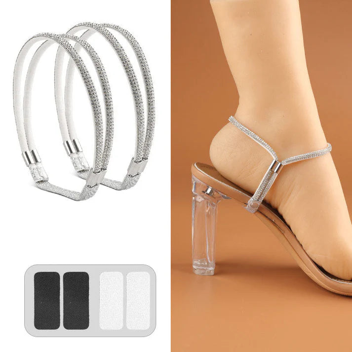 Pair of silver rhinestone elastic shoe straps with adhesive pads beside a foot in a clear-heeled sandal.