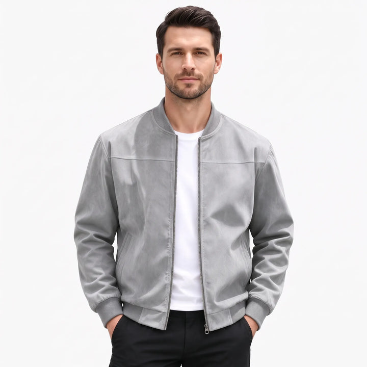 Studio shot of a man in the light gray bomber jacket, hands in black pants pockets 51