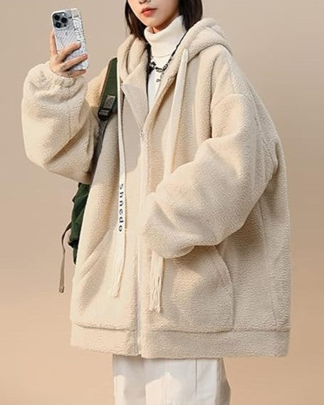 Frau in beiger Teddyfleece-Jacke mit Kapuze, Smartphone, weißem Rollkragenpullover, lässiger Stil.