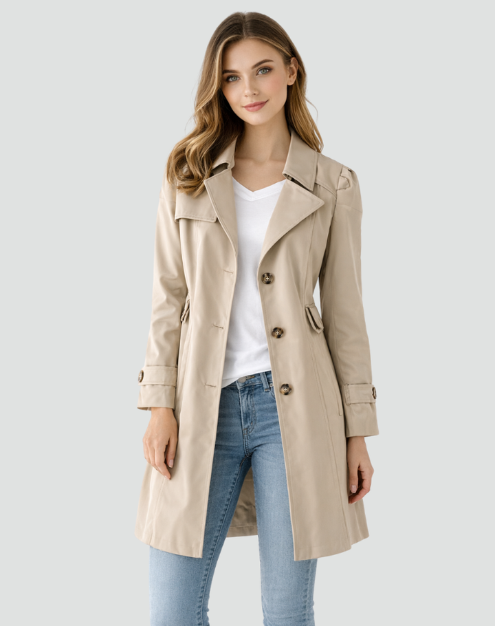 Khaki beige trench coat buttoned at the center over a white tee and jeans.