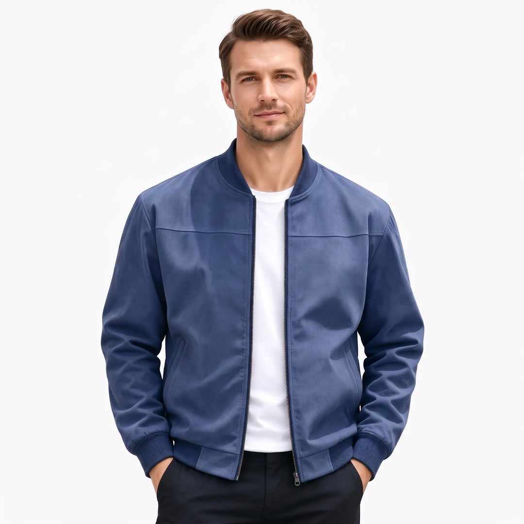 Studio shot of a man in the navy blue bomber jacket, hands in dark pants pockets 55