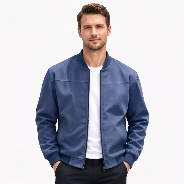 Studio shot of a man in the navy blue bomber jacket, hands in dark pants pockets 55