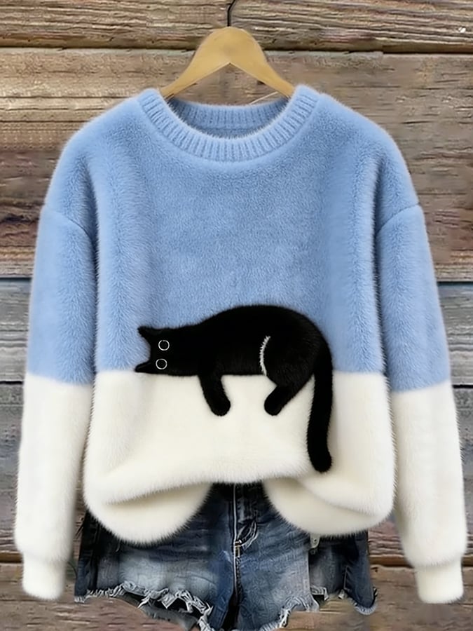 Light blue and white fuzzy colorblock sweater with a lounging black cat design, hanging on a wooden wall above denim shorts. 2
