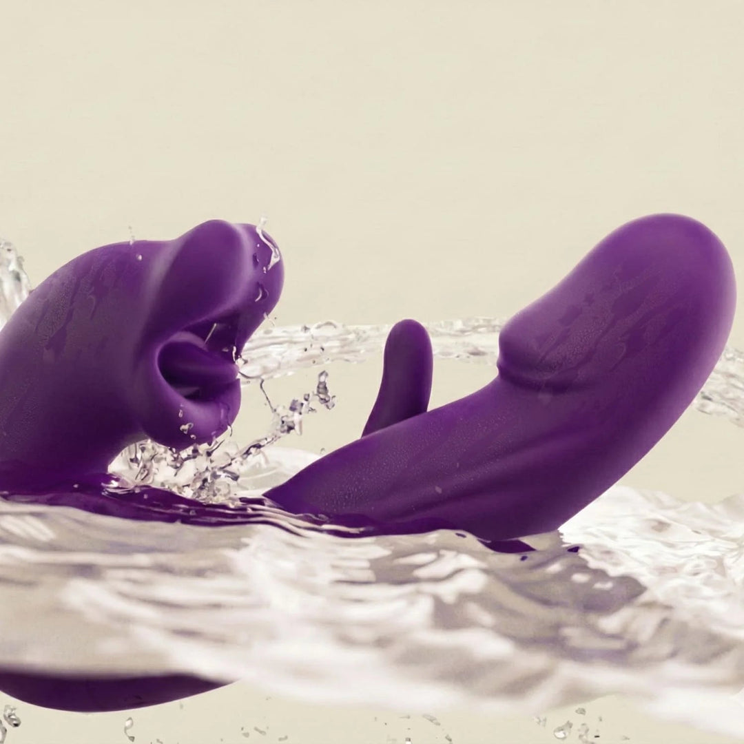 Purple silicone dual-motor massager splashing in water against a cream background, showing its waterproof design with a tongue-like tip and curved shaft. 3