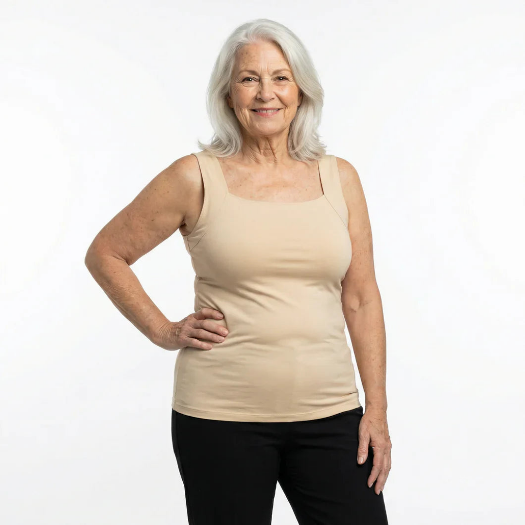 Smiling woman with long white hair poses in the beige square-neck tank with black pants, one hand on her hip. 5
