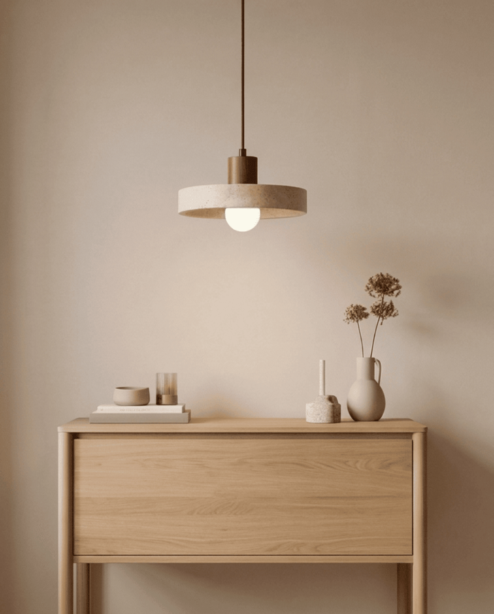 Travertine pendant light, another view, over a light oak console with books and dried flowers.