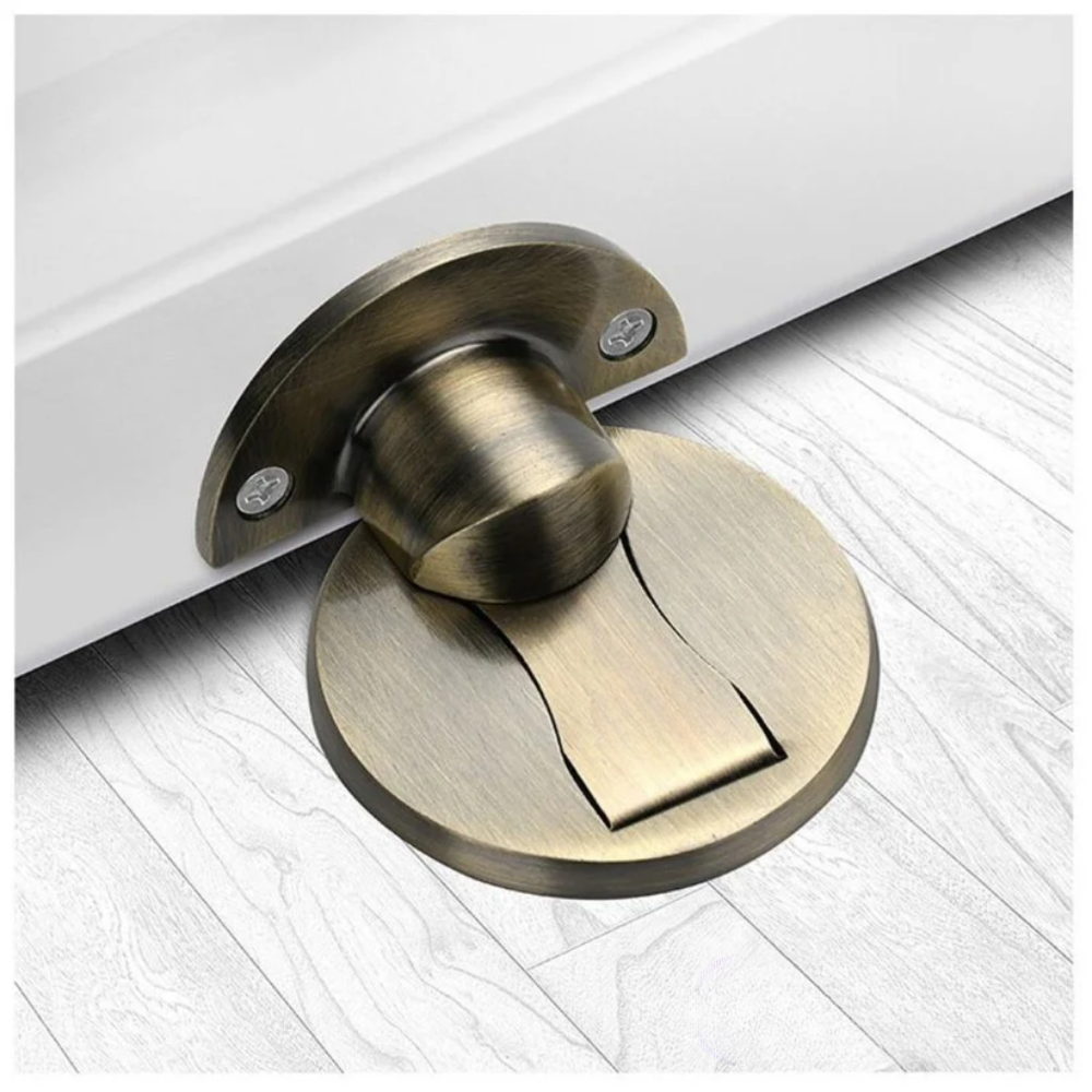 Dark antique bronze finish door stopper with a brushed look, catching the door's bottom edge above whitewashed floorboards. 4