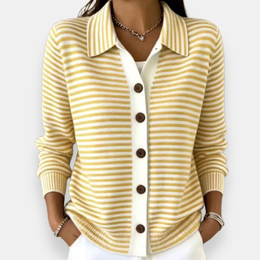 Woman wearing the collared cardigan in yellow and white stripes with brown buttons, white placket, ribbed cuffs, hands in pockets. 6