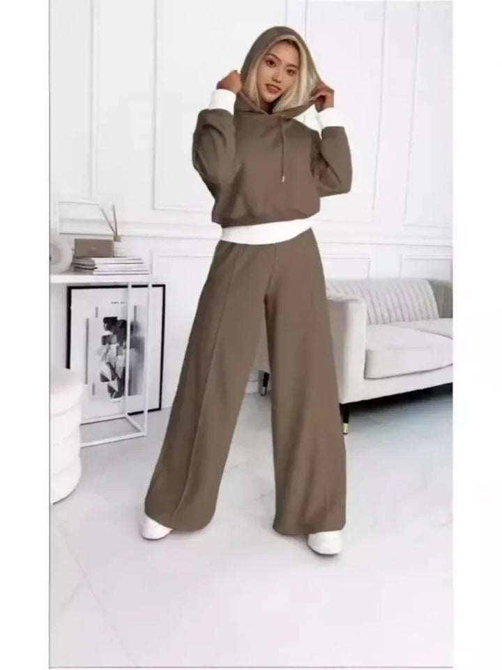 Model with hood up in a brown hoodie and wide-leg pants with white trim, full-length view 5