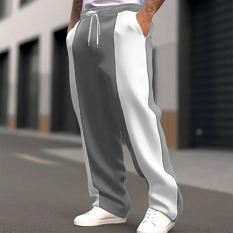 Cropped street shot of gray and white color-block sweatpants with drawstring waist and white sneakers 5