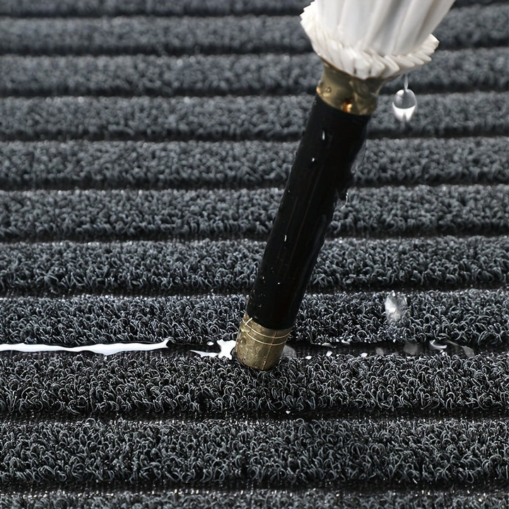 Grey striped doormat detail with water drops pooling between the ridges.