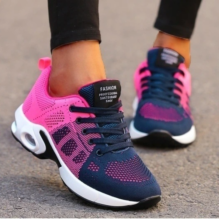 Navy and hot pink mesh sneakers with white cushioned soles worn by a model in black leggings on pavement. 12