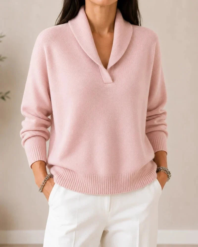 Front view of the sweater in soft pink worn by a model with white trousers, hands in pockets. 12