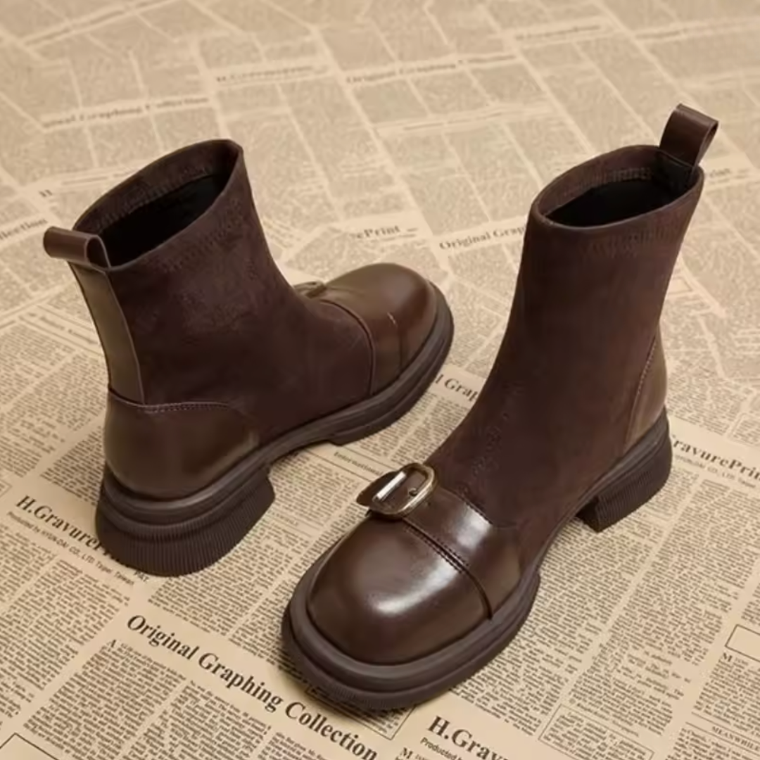 Brown suede boots shown from the side and back, with leather heel counters, pull tabs and a brass-toned buckle on the toe strap.