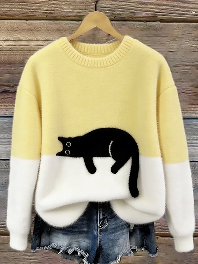 Pale yellow and white fuzzy colorblock sweater with a black cat lying along the color divide, hung on a wooden wall. 8