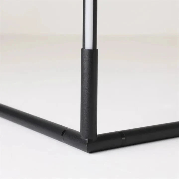 Close-up of the black metal joint where the vertical light tube meets the two base legs of the lamp. 7