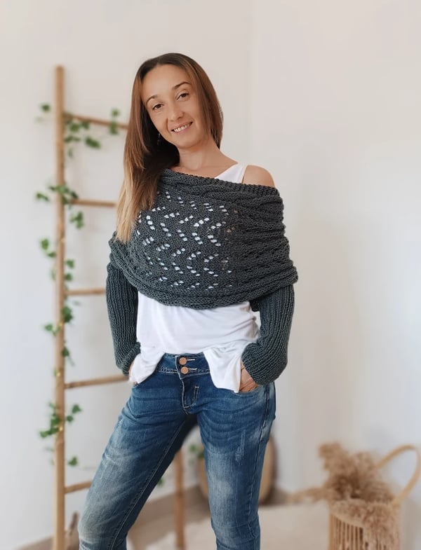 Charcoal gray wrap worn off one shoulder over a white tank top, with long ribbed sleeves and hands in jeans pockets. 2