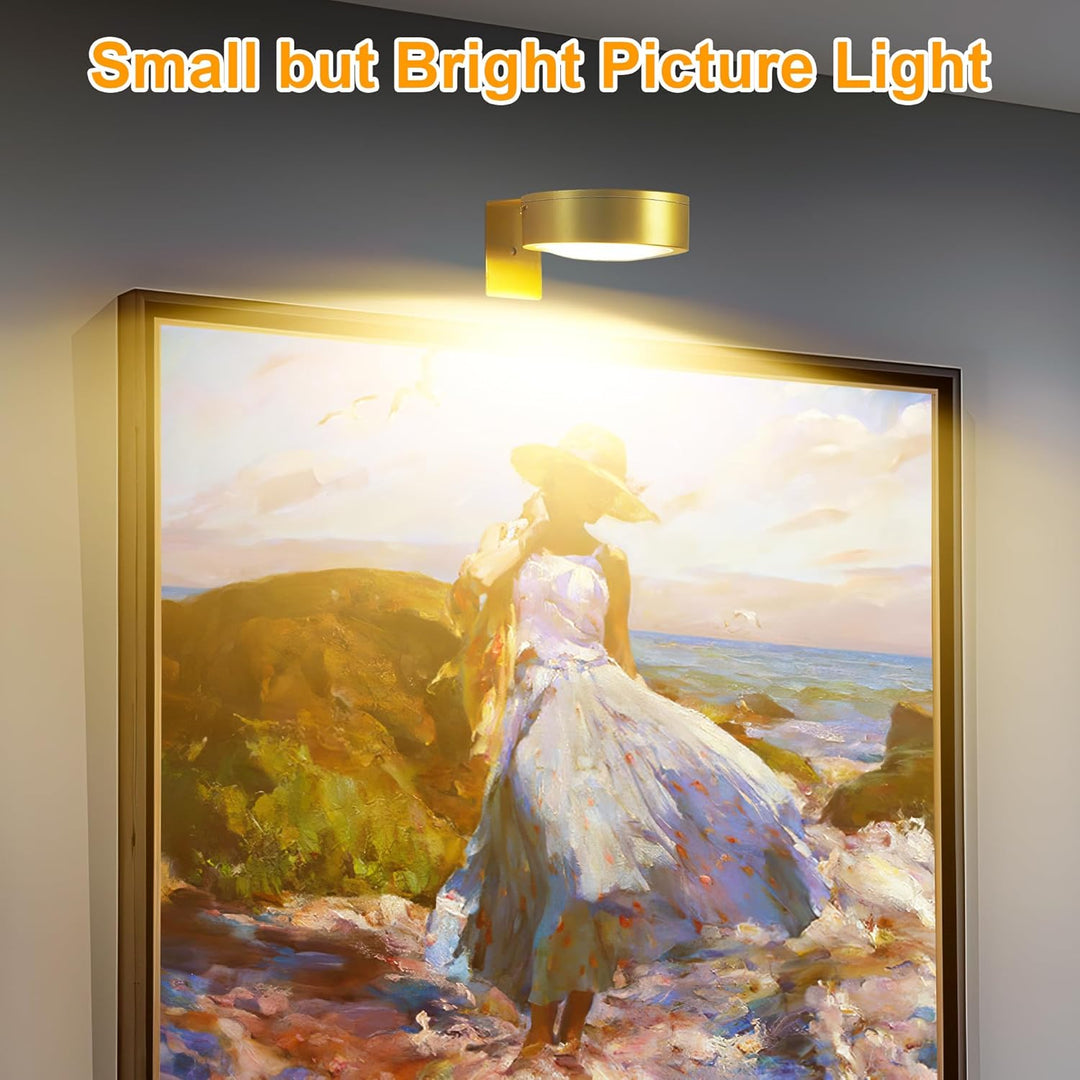 Gold round light mounted above a framed painting of a woman in a sun hat on a beach, casting warm light. 4
