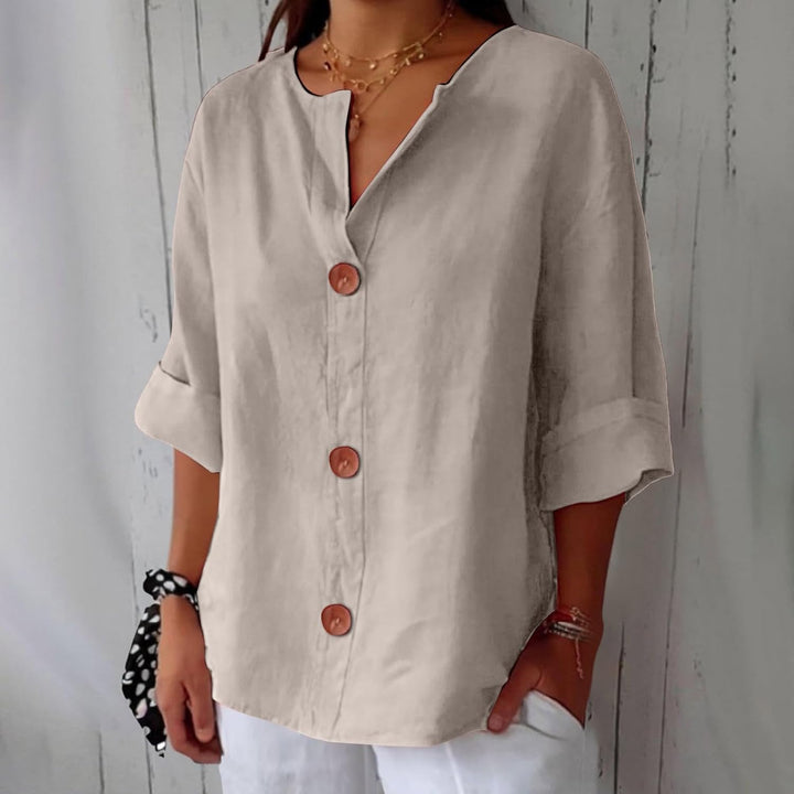 Olivia loose linen blouse in beige with a notched V-neck, three brown buttons and rolled cuffed sleeves.