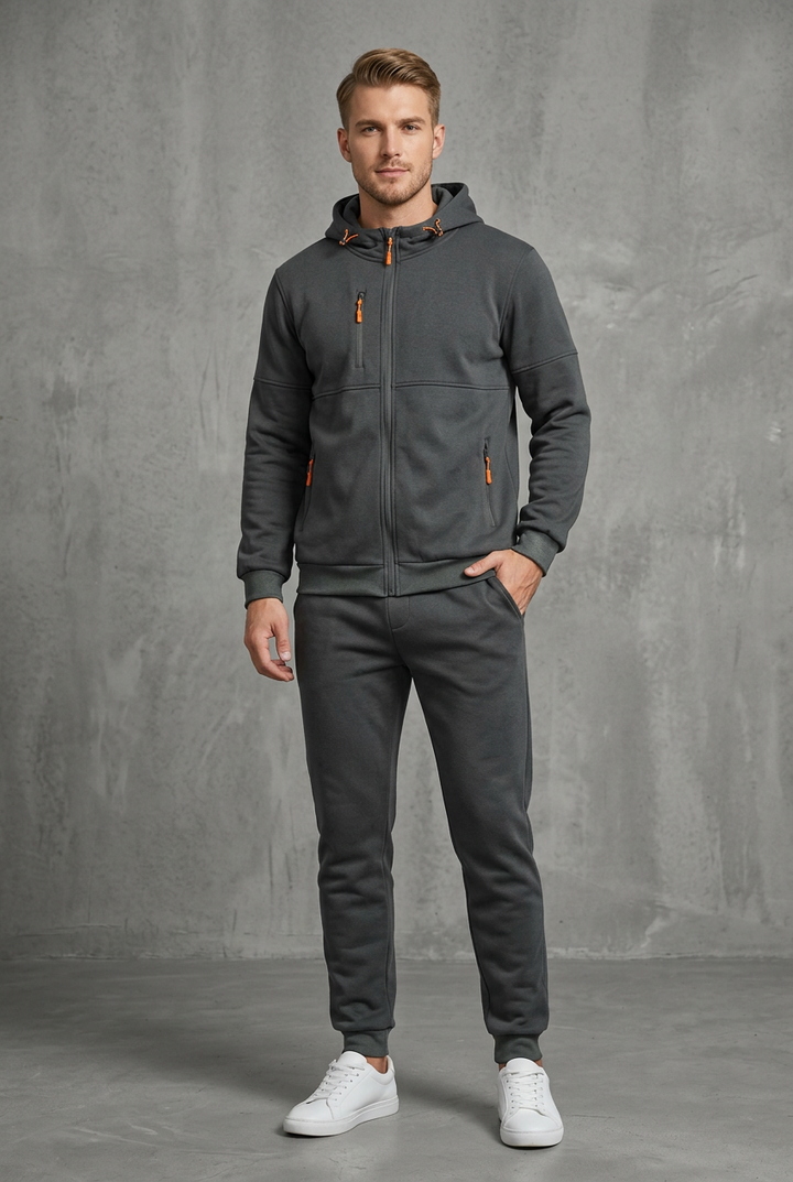 Front view of the dark gray zip hoodie and joggers with orange zipper pulls on a model 4