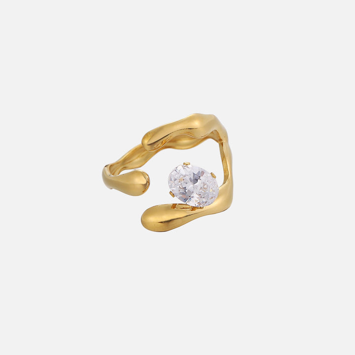 Same open gold-tone ring from a different angle, showing the organic curved band ends and the prong-set oval clear crystal. 2