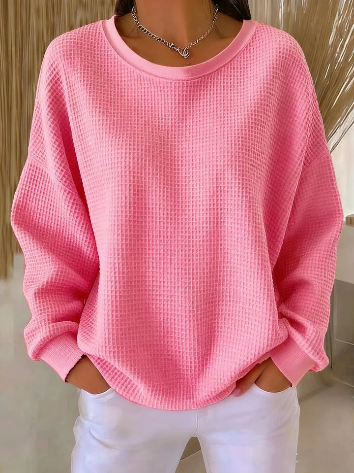 Soft pink waffle-texture pullover with drop shoulders and hands in white pants pockets.