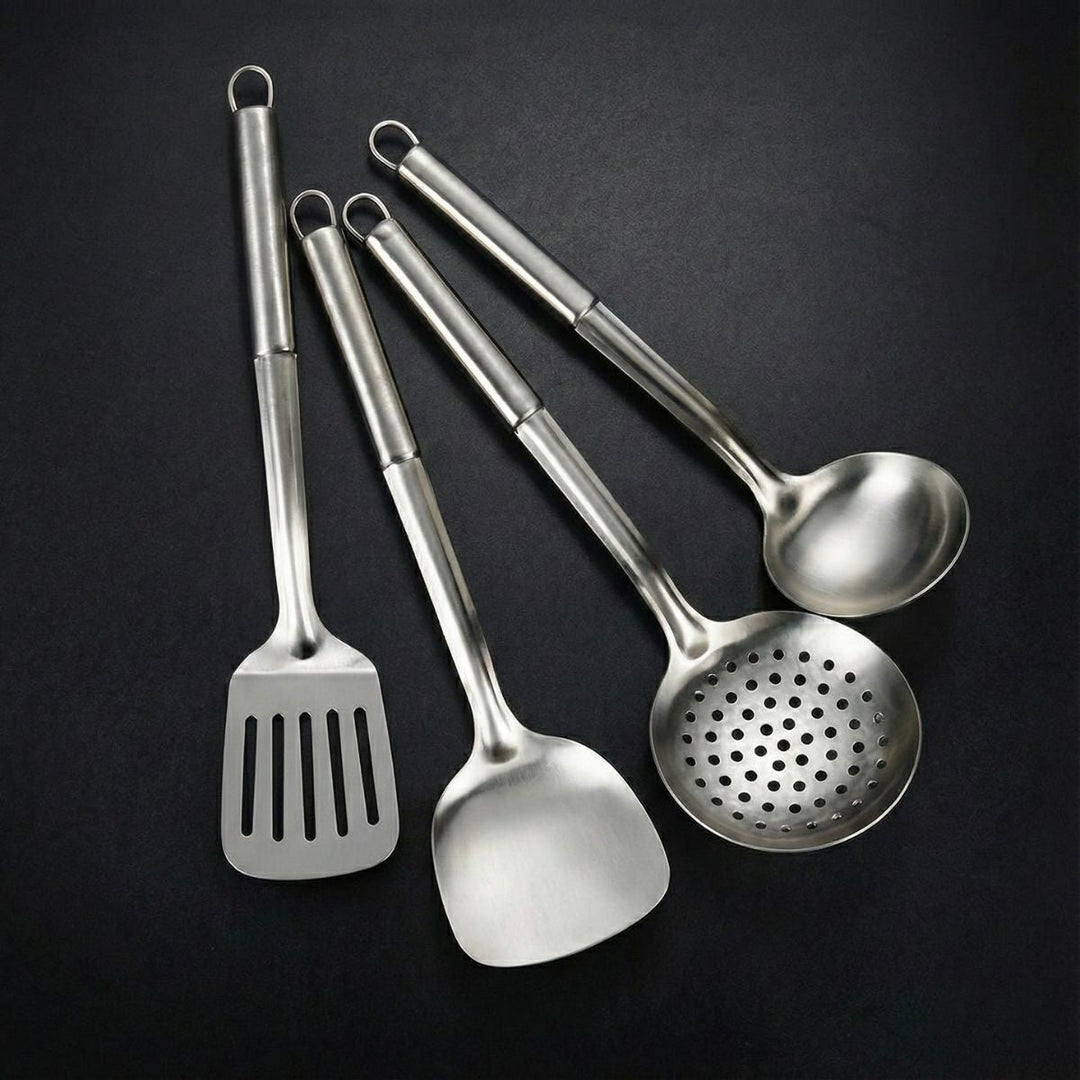 Four steel utensils with hanging loops: a slotted turner, a solid spatula, a perforated skimmer and a ladle.