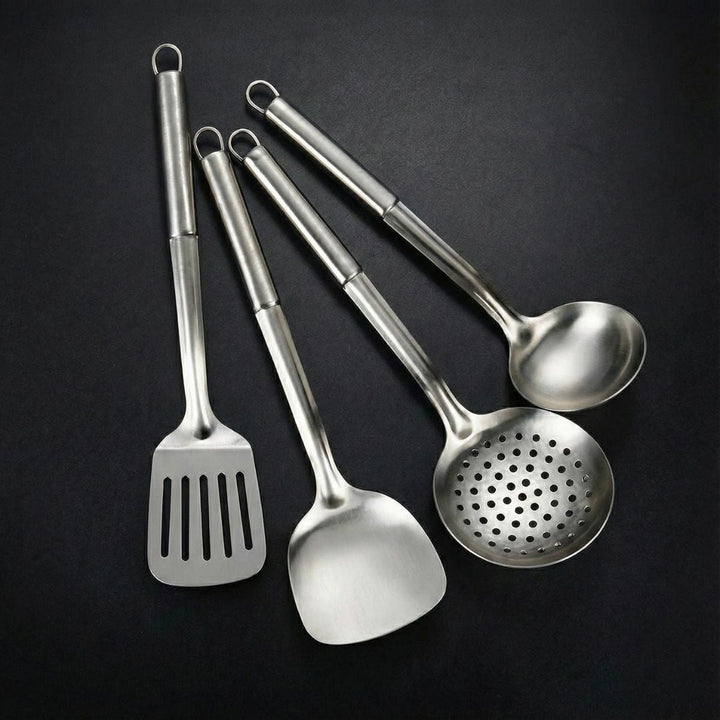 Four steel utensils with hanging loops: a slotted turner, a solid spatula, a perforated skimmer and a ladle.