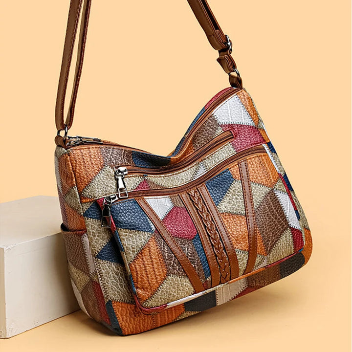 Patchwork bag angled on a peach background beside a cream block, showing the braided brown strip, two zip pockets and strap. 4