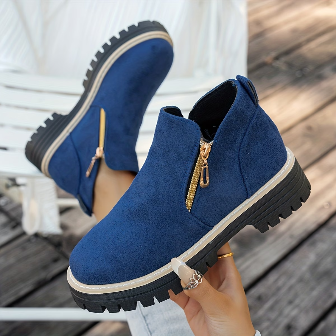 Royal blue suede-look ankle boots with gold side zippers and thick treaded black soles.