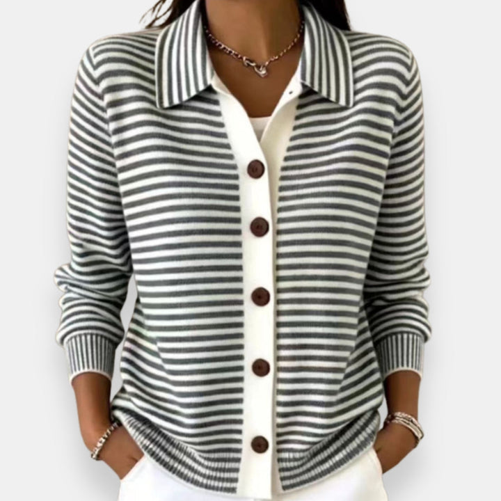 Woman wearing the collared cardigan in gray and white stripes with brown buttons, white placket, ribbed cuffs, hands in pockets. 3