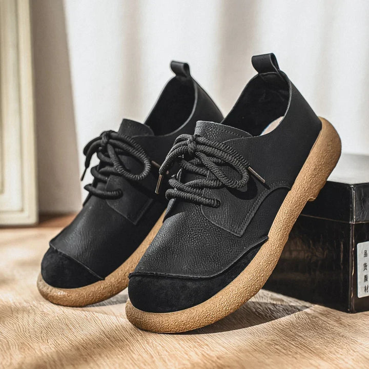 Black lace-up shoes with tan soles resting beside a black shoe box 6