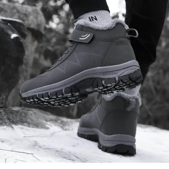 Person in gray fleece-lined boots on a snowy rock, rear foot raised to show the sole 8