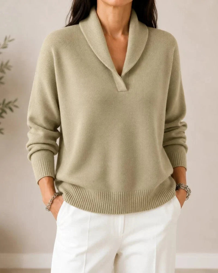 Front view of the sweater in a soft sage or khaki green, worn by a model with white trousers. 9