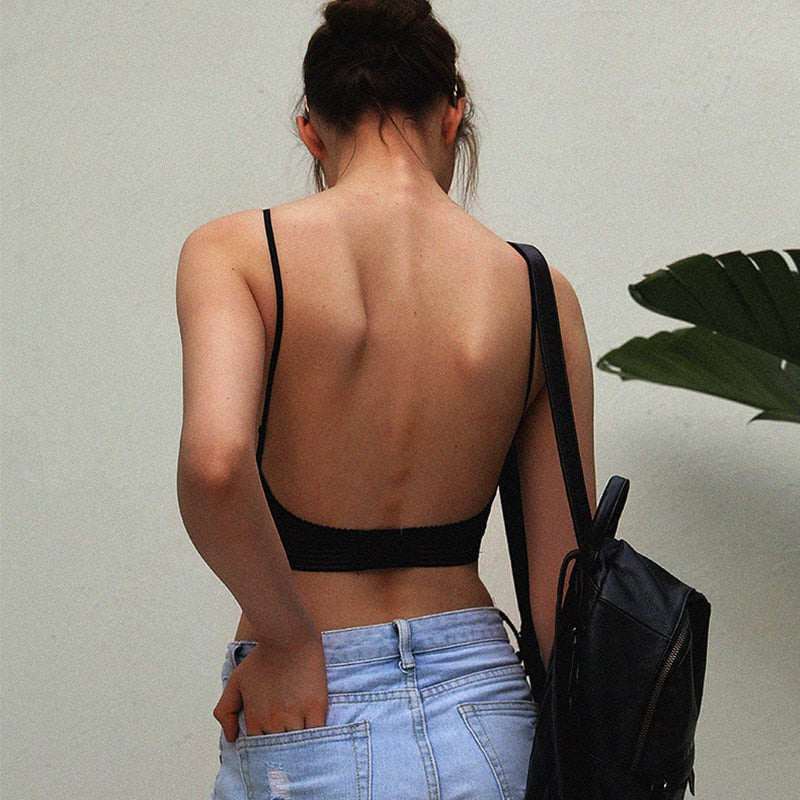 Back view of a woman in the black bra with thin straps and open back, carrying a backpack 2