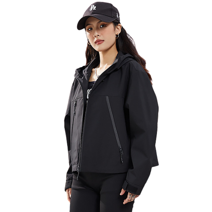 Angled front view of the black jacket on a model with a black cap, one hand resting at her side. 16